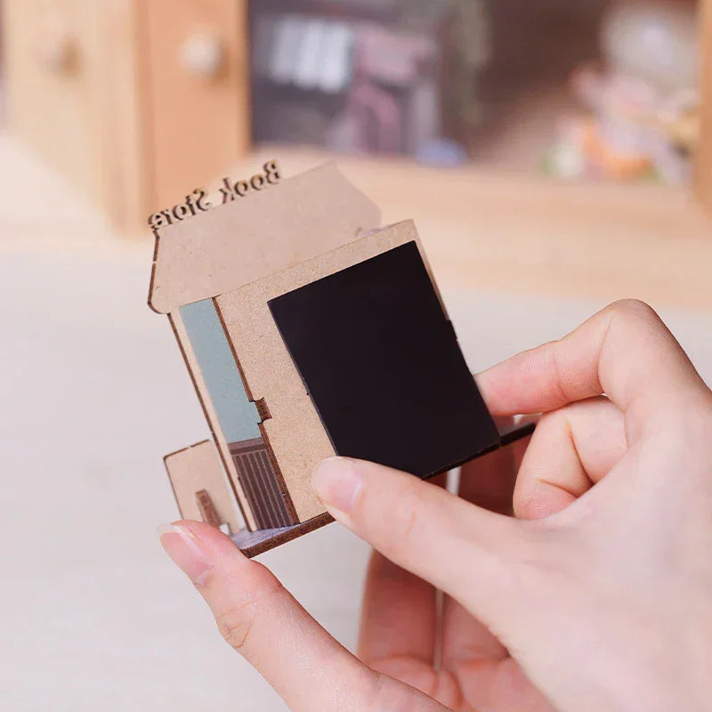 Hände halten ein braunes Miniatur-Bücherregal mit der Aufschrift Buchhandlung
