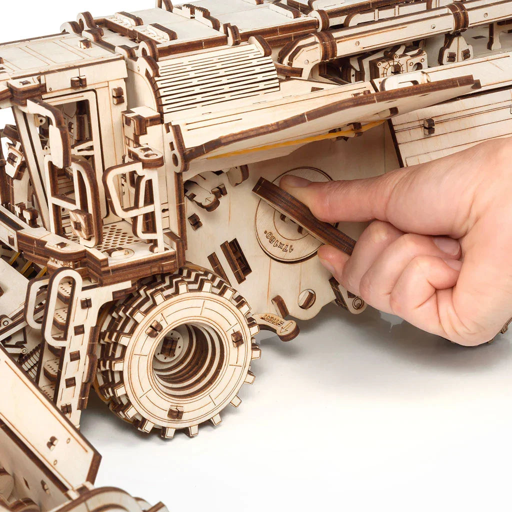 Hand setzt ein Holzteil in ein Holzmodell eines Lastwagens ein