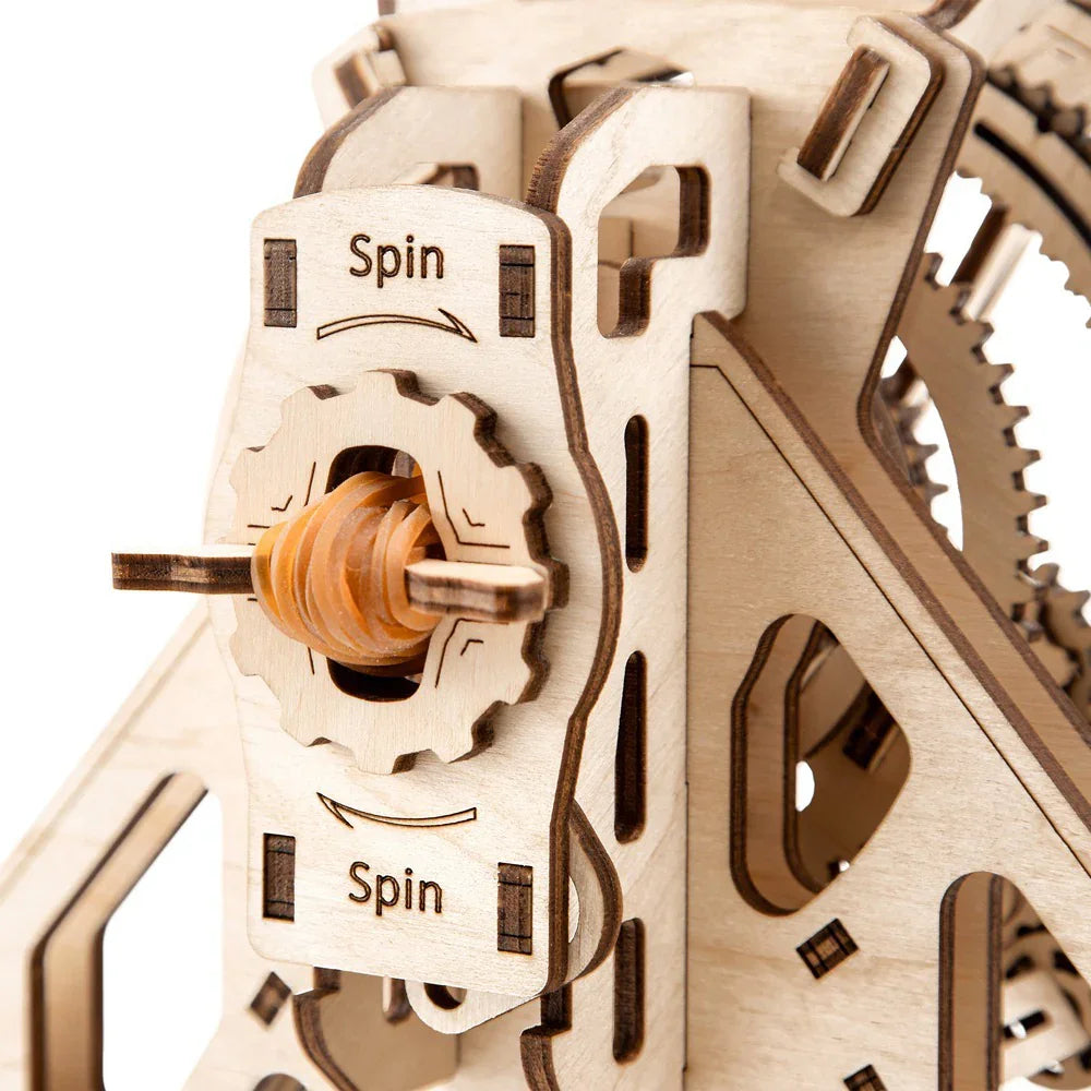 Nahaufnahme eines hölzernen Zahnradmechanismus mit der Aufschrift Spin und einem orangefarbenen Schneckengetriebe