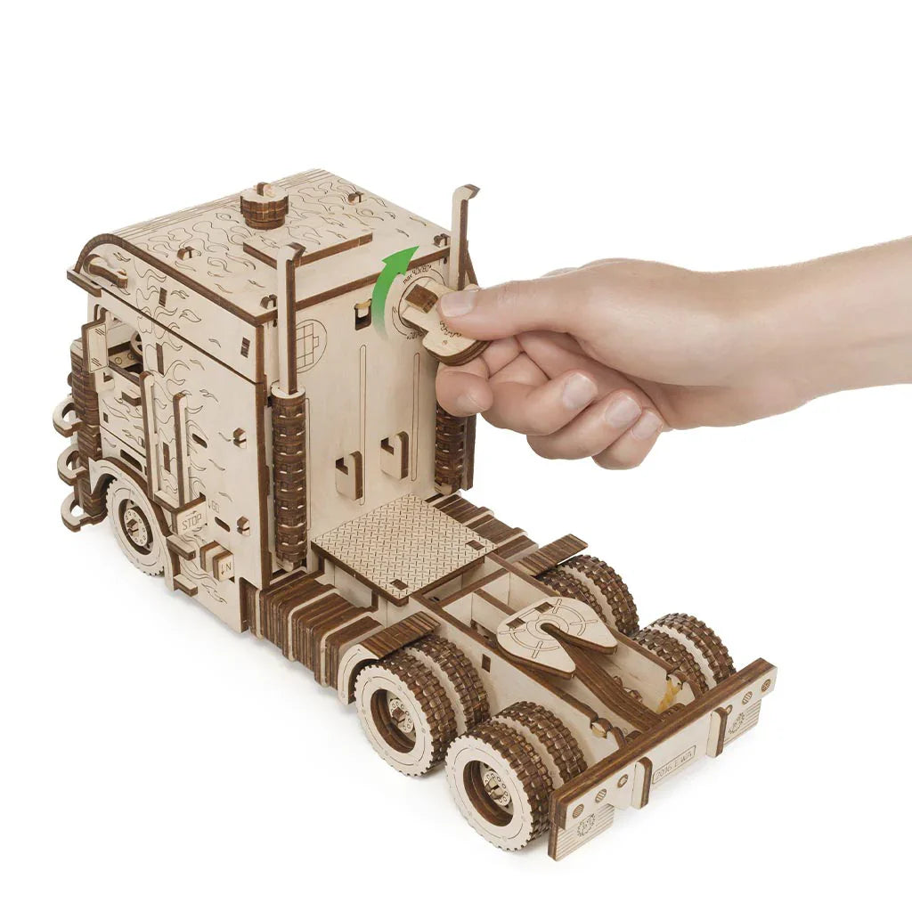 Hand dreht einen Knopf an einem Holz-LKW-Modell