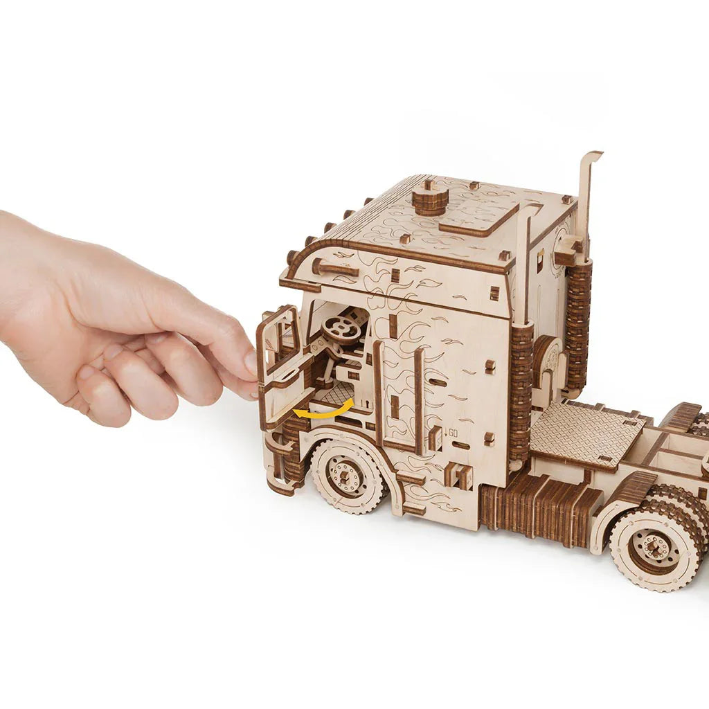 Hand öffnet die Tür eines Holz-LKW-Modells mit Flammenmuster