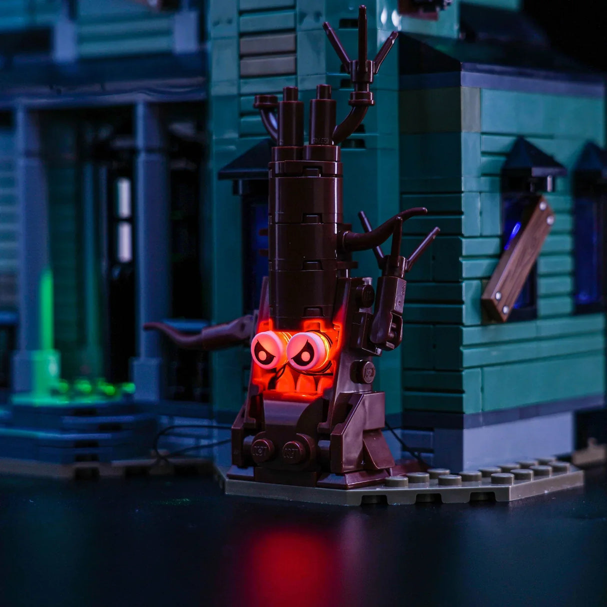 Ein LEGO Baum mit leuchtenden roten Augen vor einem grünen LEGO Haus