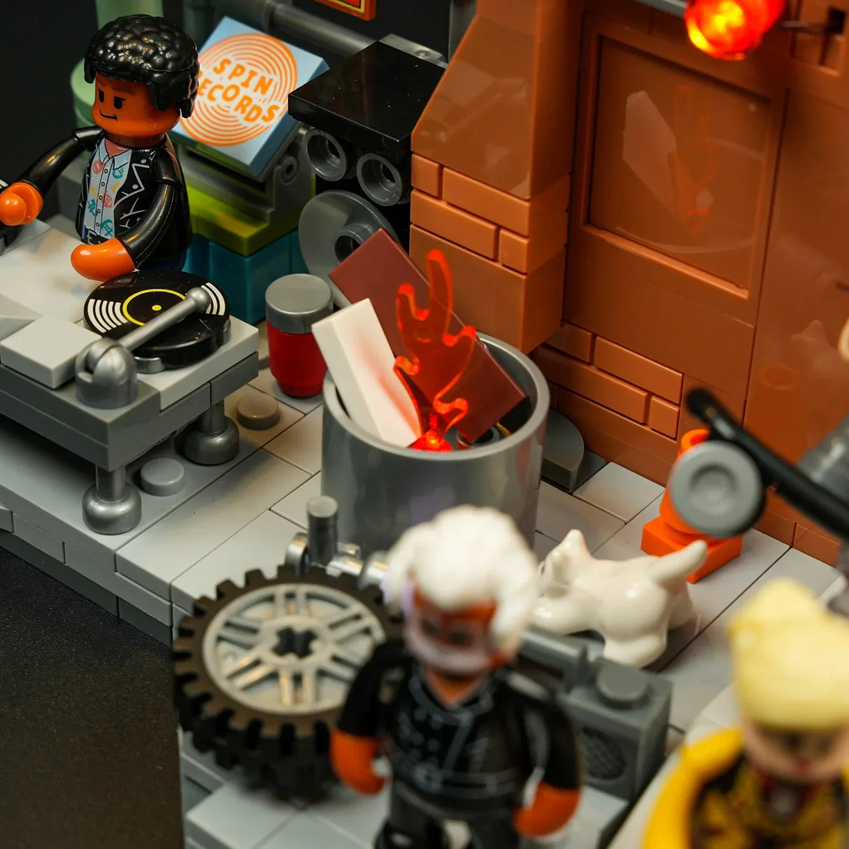 Lego-Figuren in einer Szene mit DJ-Pult, Schallplatten und einem Mülleimer mit Flammen