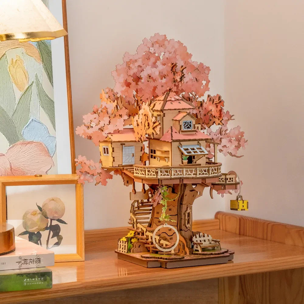 Baumhaus-Modell aus Holz mit rosa Blättern auf einem Holztisch