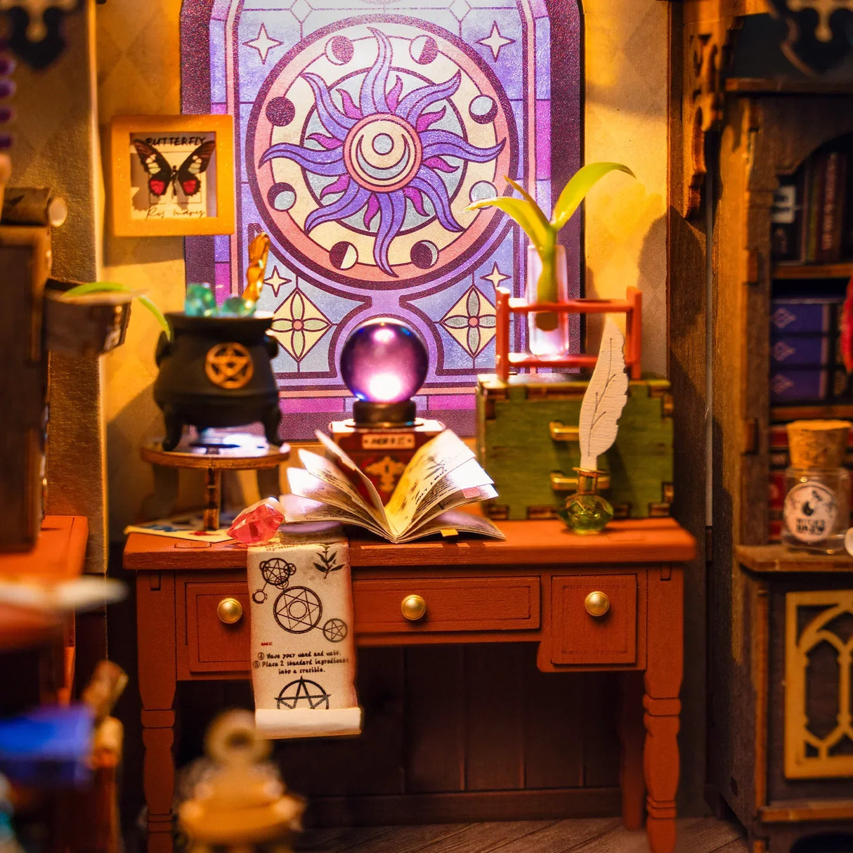 Ein Miniatur-Hexenarbeitszimmer mit einem Schreibtisch, Zauberbuch, Kessel und einem bunten Fenster