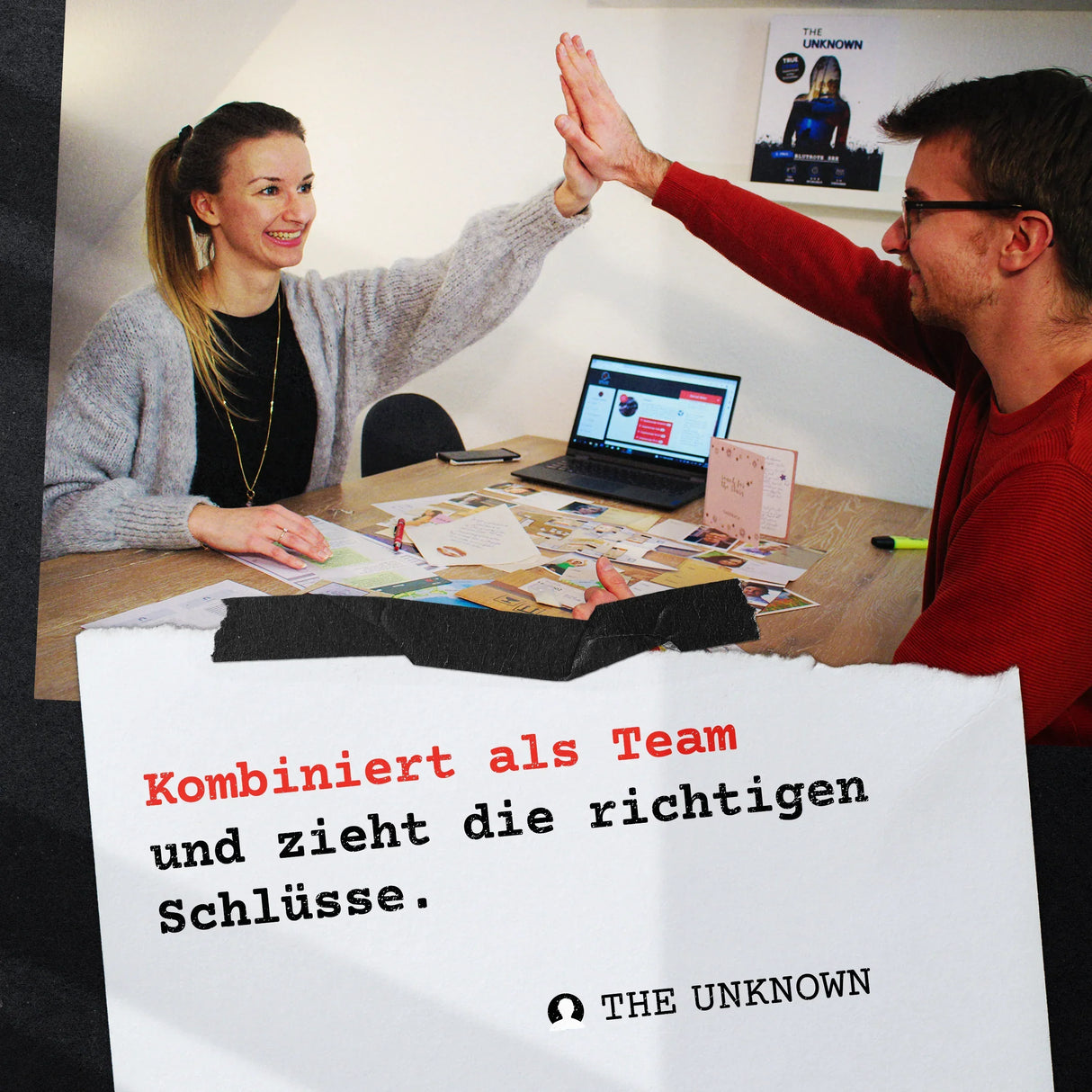 Zwei Personen geben sich High Five über einem Tisch mit Laptop und Dokumenten