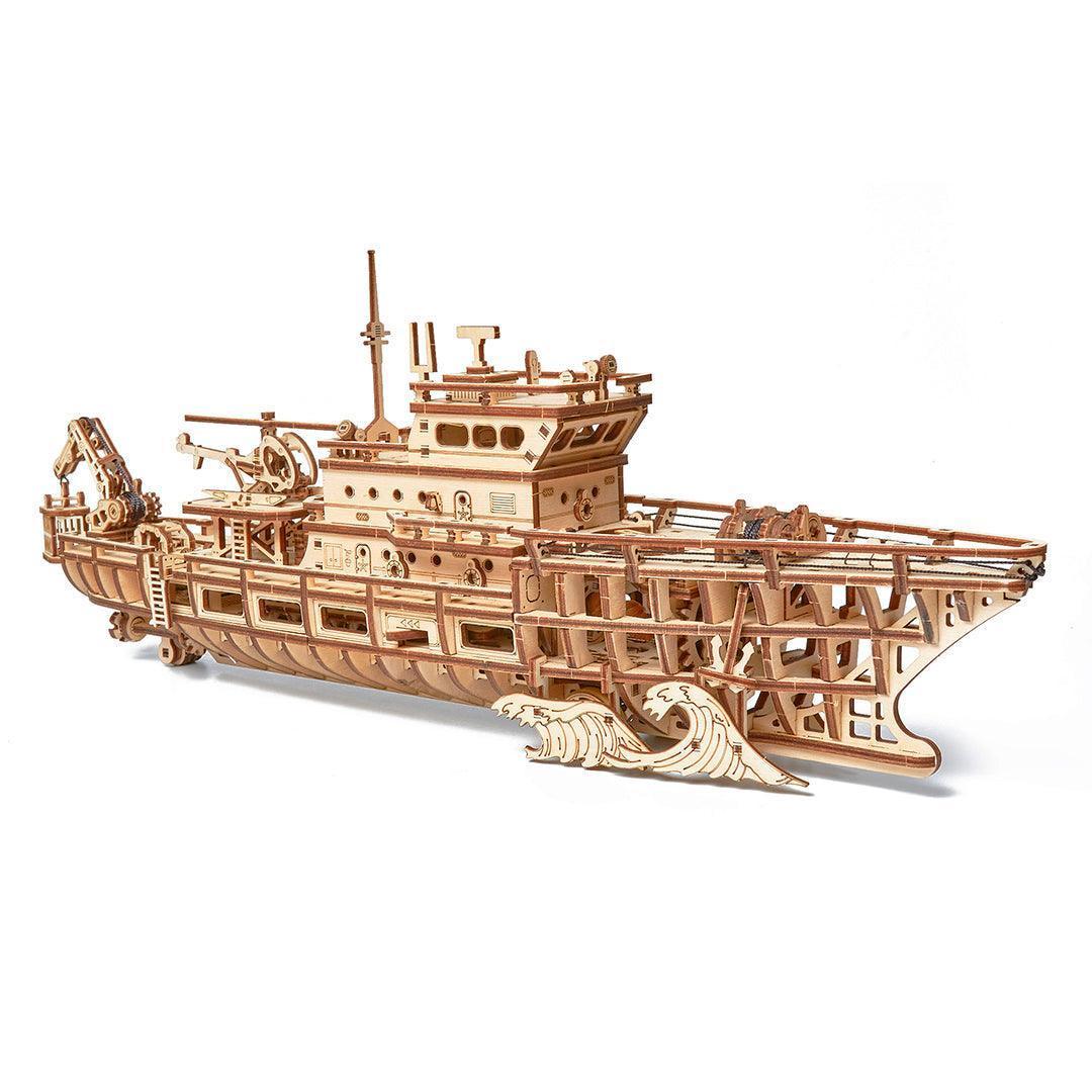 WoodTrick Forschungsschiff 3D-Holzbausatz – Schrägansicht von vorne auf das fertige Holzschiff mit stilvollem Wellen-Standfuss.