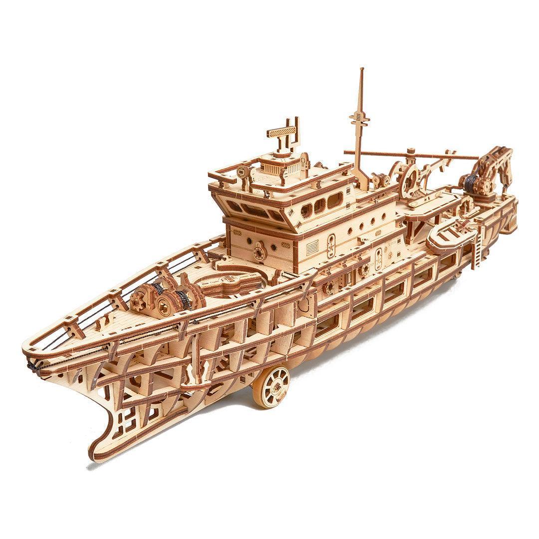 WoodTrick Forschungsschiff mechanischer Bausatz – Erhöhte Draufsicht von vorne auf das detaillierte Vordeck und das offene Rumpfdesign mit Rädern.