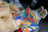 Entspanntes Reisen dank QwiToy – Ein Kind beschäftigt sich im Autositz mit dem bunten 3D-Pop-up-Buch. 58347556241792 58347556274560 58347556307328 58347556340096