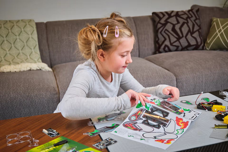 Kind beklebt die Bauteile des CircuitMess Sparkly Bausatzes mit bunten Stickern