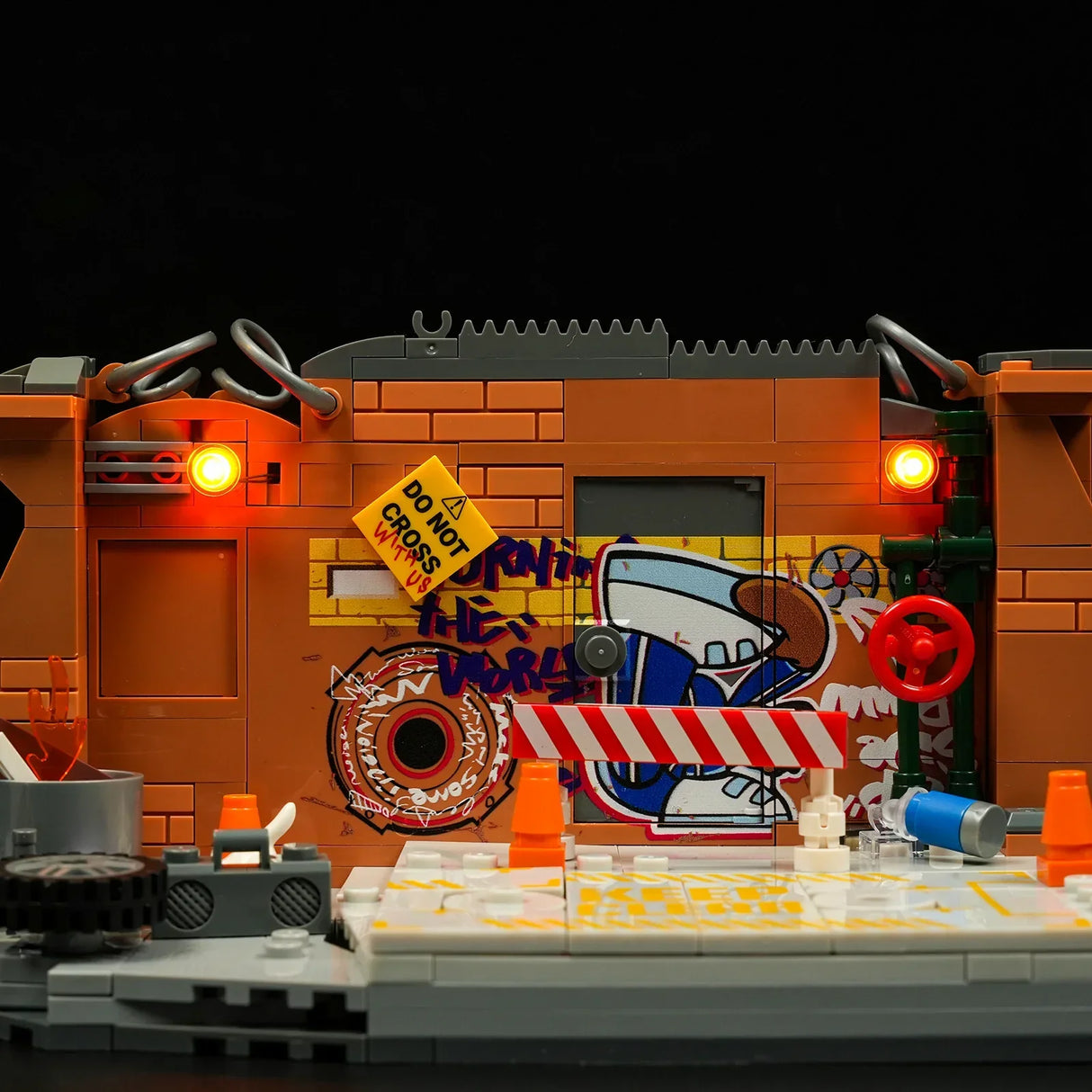 Eine Lego-Szene mit Graffiti an einer Ziegelwand, Warnschildern und orangefarbenen Lichtern