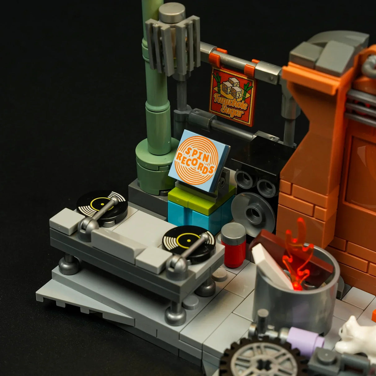 Lego-Szene mit Plattenspielern, Lautsprechern, einem Schild mit der Aufschrift Spin Records und einem Feuer in einem Eimer
